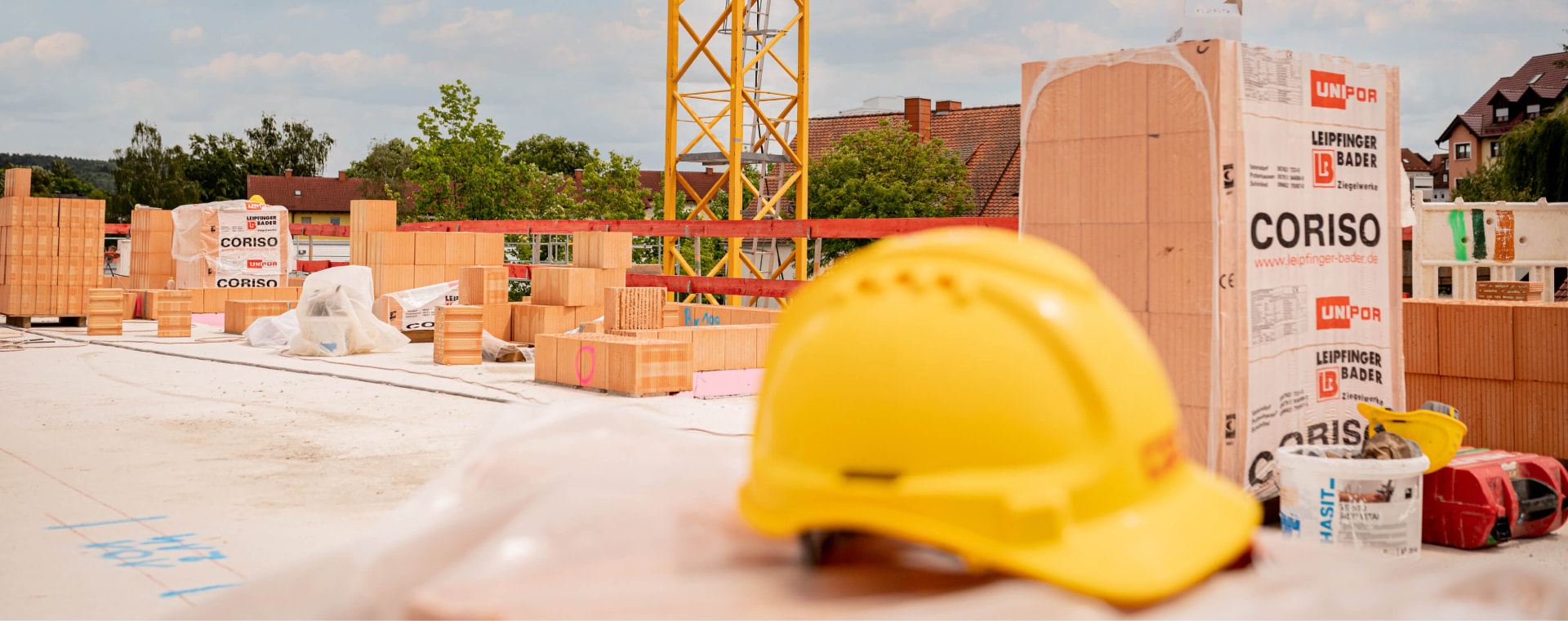 HD-Bau-Baustelle mit Mauerziegeln, gelbem Bauhelm und Kran im Hintergrund